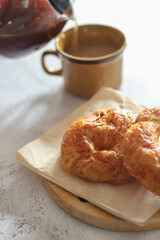 A croissant served with coffee is placed on a white table.