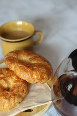 A croissant served with coffee is placed on a white table.