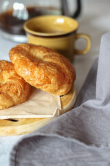 A croissant served with coffee is placed on a white table.