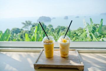 Mango yogurt smoothie set up on wooden plate