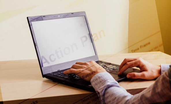Close up shot of a man working on computer with blended image of an action plan words. Business
