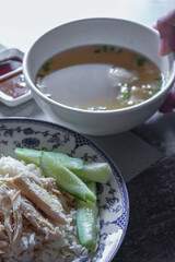 Rice Steamed With Chicken Soup Hainanese served in a Chinese style dish with soy sauce and broth on a gray table.