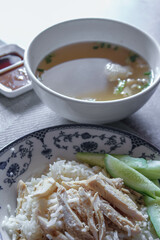 Rice Steamed With Chicken Soup Hainanese served in a Chinese style dish with soy sauce and broth on a gray table.