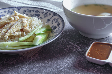rice steamed with chicken soup served in a Chinese style plate with soy sauce and broth on a gray table