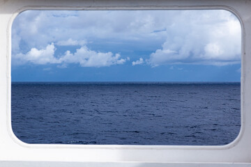 Fototapeta premium Rectangular steel window on a ship overlooking the open sea and sky.