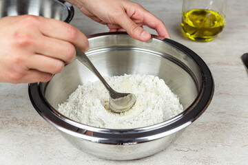 Closeup of woman hands while preparing a recipe. Flour in a bowl. Cooking at home