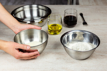 Cooking at home. Ingredients for the preparation of a recipe. Flour, olive oil, wine. Hands taking a bowl