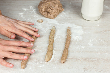 The woman's hands extended the paste on a marble table to prepare the Apulian taralli. Cooking at home