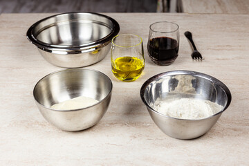 Ingredients for the preparation of a recipe. Flour in an aluminum bowl, olive oil, wine