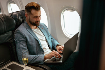 Bearded man working on notebook in airplane