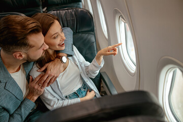 Happy couple in love looking out the window in plane