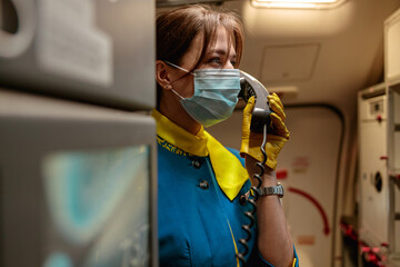 Woman stewardess in medical mask talking on telephone in airplane