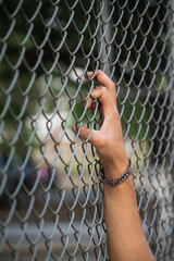 The young man's hand clinging to the lattice fence outside the building due to imprisonment. The idea of imprisoning prisoners of war to prevent escaping and to negotiate with the enemy.