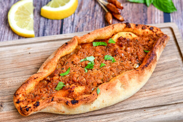  Traditional Turkish cuisine. Baked Pide dish with  cheese and  herbs on  wooden background.  Turkish pizza pide
