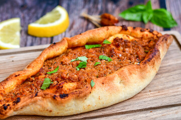  Traditional Turkish cuisine. Baked Pide dish with minced  beef, tomatoes and  herbs on  wooden background.  Turkish pizza pide