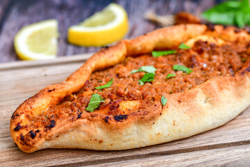  Traditional Turkish cuisine. Baked Pide dish with minced  beef, tomatoes and  herbs on  wooden background.  Turkish pizza pide