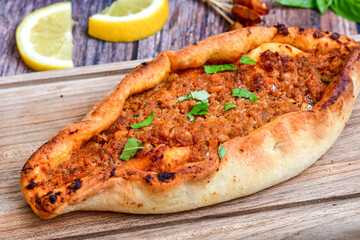  Traditional Turkish cuisine. Baked Pide dish with minced  beef, tomatoes and  herbs on  wooden background.  Turkish pizza pide