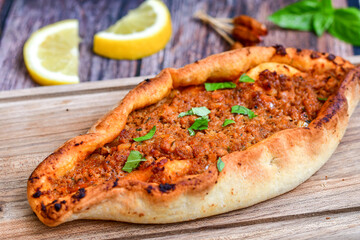  Traditional Turkish cuisine. Baked Pide dish with minced  beef, tomatoes and  herbs on  wooden background.  Turkish pizza pide