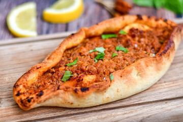  Traditional Turkish cuisine. Baked Pide dish with minced  beef, tomatoes and  herbs on  wooden...
