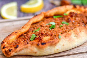  Traditional Turkish cuisine. Baked Pide dish with minced  beef, tomatoes and  herbs on  wooden background.  Turkish pizza pide