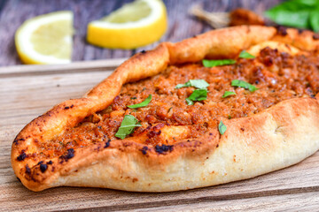  Traditional Turkish cuisine. Baked Pide dish with minced  beef, tomatoes and  herbs on  wooden background.  Turkish pizza pide