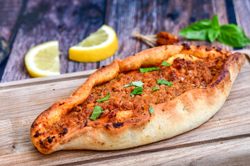  Traditional Turkish cuisine. Baked Pide dish with minced  beef, tomatoes and  herbs on  wooden background.  Turkish pizza pide