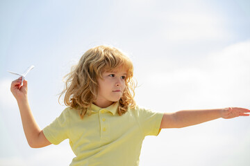 Child pilot with toy airplane dreams of traveling in summer in nature. Kids dreams. Child plays with a toy plane and dreams of becoming a pilot.