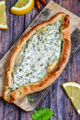  Traditional Turkish cuisine. Baked Pide dish with  cheese and  herbs on  wooden background. ...