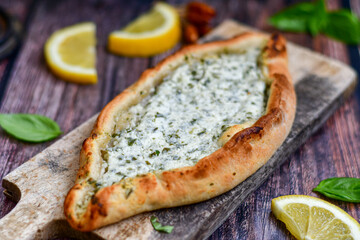  Traditional Turkish cuisine. Baked Pide dish with  cheese and  herbs on  wooden background.  Turkish pizza pide