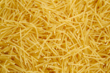 Delicious noodles texture. Textured background with yellow pasta. Macaroni for soup. Uncooked Italian vermicelli.  Healthy food and eating concept.