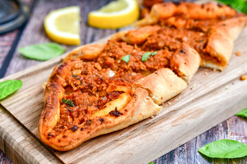  Traditional Turkish cuisine. Baked Pide dish with minced  beef, tomatoes and  herbs on  wooden background.  Turkish pizza pide