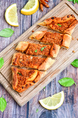  Traditional Turkish cuisine. Baked Pide dish with minced  beef, tomatoes and  herbs on  wooden background.  Turkish pizza pide