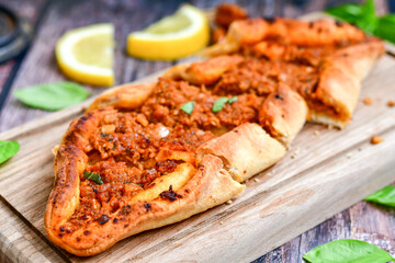  Traditional Turkish cuisine. Baked Pide dish with minced  beef, tomatoes and  herbs on  wooden background.  Turkish pizza pide