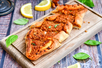  Traditional Turkish cuisine. Baked Pide dish with minced  beef, tomatoes and  herbs on  wooden background.  Turkish pizza pide