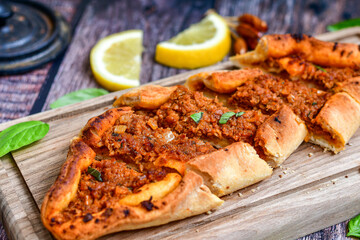  Traditional Turkish cuisine. Baked Pide dish with minced  beef, tomatoes and cheese on  wooden background.  Turkish pizza pide