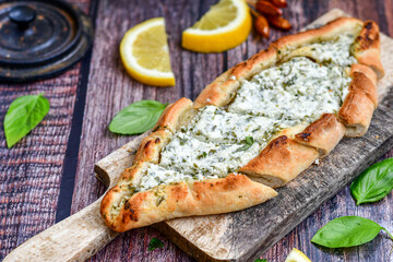  Traditional Turkish cuisine. Baked Pide dish with minced  beef, tomatoes and cheese on  wooden background.  Turkish pizza pide