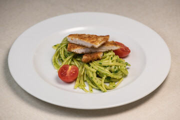 Turkey cutlet and Green spinach spaghetti with cheese and tomato on wooden table. High quality photo