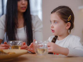 Family drinking tea with cookies on kitchen at home. Mother and daughter having fun, happy moment together at home.