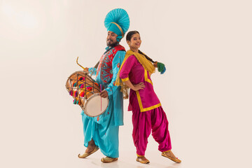 Sikh couple performing bhangra and playing drum during Baisakhi celebration
