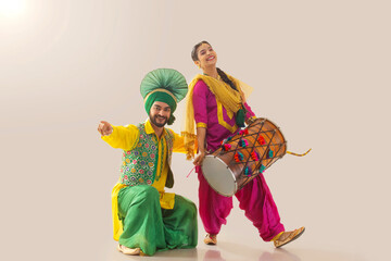 Sikh couple performing bhangra and playing drum during Baisakhi celebration