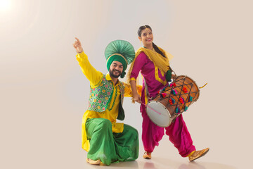 Sikh couple performing bhangra and playing drum during Baisakhi celebration