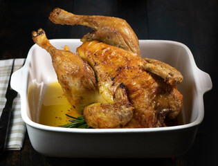 Roast chicken on a white plate, on a black wooden background. High quality photo