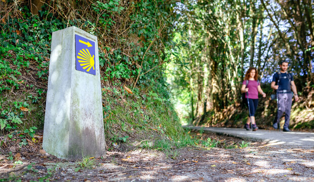 Signpost of Saint James way with pilgrims walking in the background