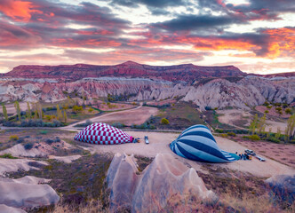 Preparing balloons for flight in Cappadocia. Colorful sunrise in Red Rose valley, Goreme village location, Turkey, Asia. Traveling concept background..
