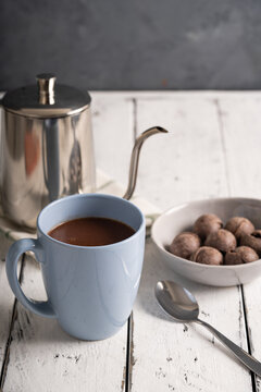 a mug of hot chocolate with tablea on the side on white wood background