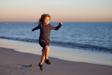 Child running through water close to shore along the sea beach. A boy runs along the sea coast. Rest of children on summer vacation. Summer vacation with child.