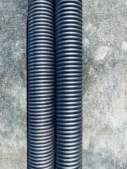 two metallic springs lie parallel to each other on a gray surface