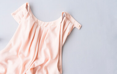 Beautiful female pink blouse or dress lies on a gray background