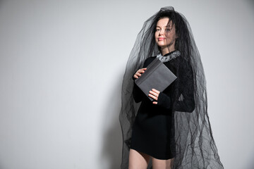 beautiful woman in a black wedding dress with a bride veil and a book