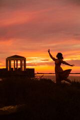 Fototapeta na wymiar silhouette of the woman on sunset at sea beach